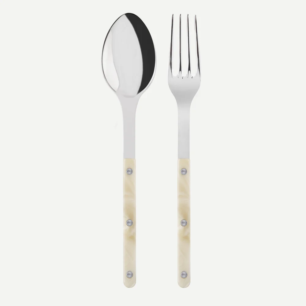 The Sabre Bistrot Shiny Serving Set – Faux Horn includes a metal spoon and fork with polished heads and marbled cream handles secured by three rivets, shown side by side on a white background.