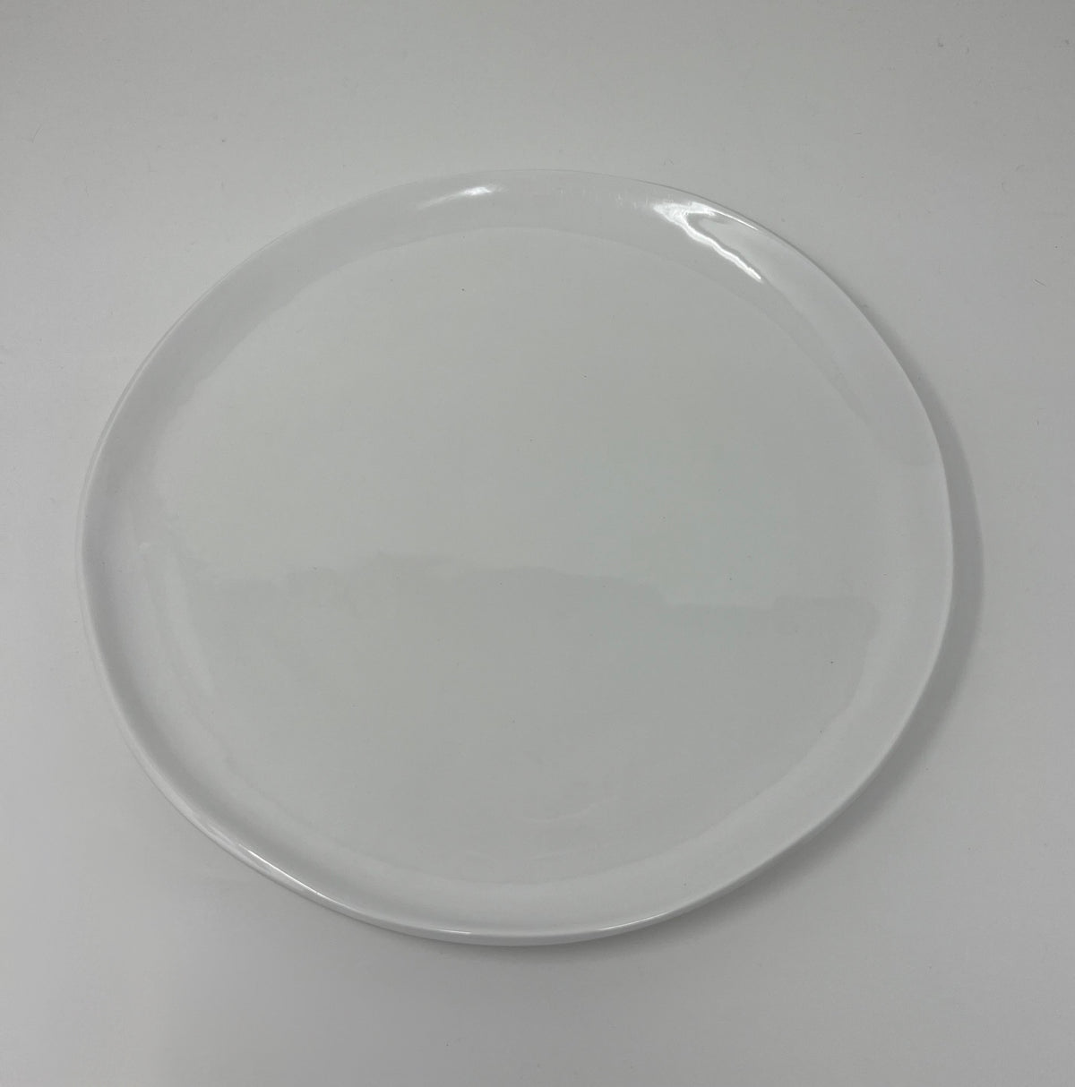 The Relish Simple White Melamine Dinnerware plate, a best seller, features a smooth surface with slightly uneven edges. Centered on a white background, this round plate is dishwasher safe.