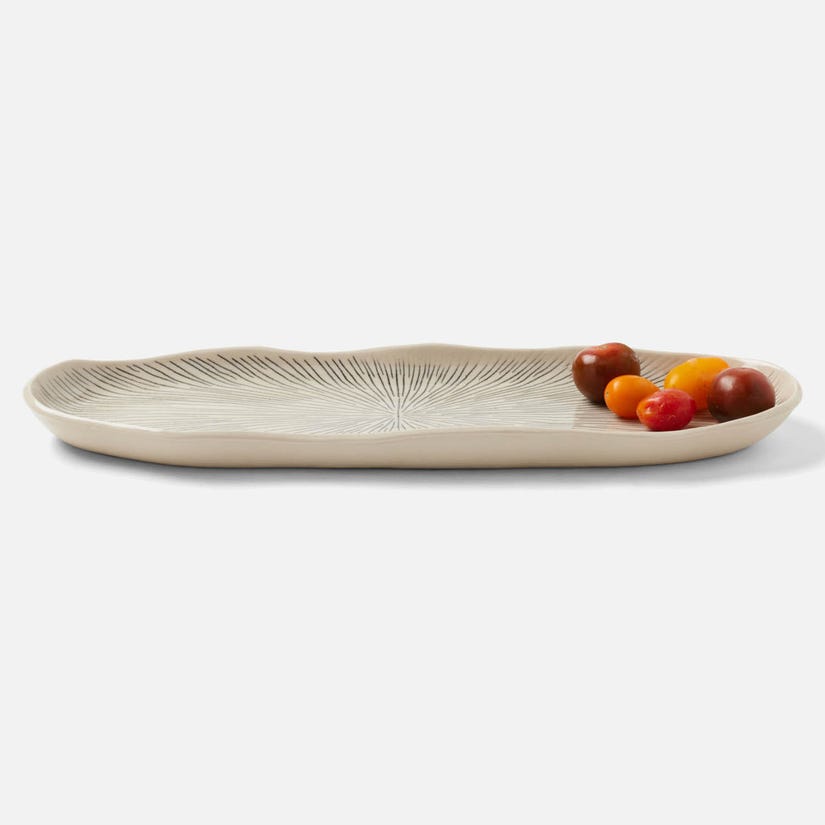 A black and cream oval ceramic platter from Blue Pheasant’s Nolan Dinnerware collection, featuring subtle leaf-like patterns and holding assorted cherry tomatoes in one corner, set against a white background.