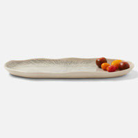 A black and cream oval ceramic platter from Blue Pheasant’s Nolan Dinnerware collection, featuring subtle leaf-like patterns and holding assorted cherry tomatoes in one corner, set against a white background.