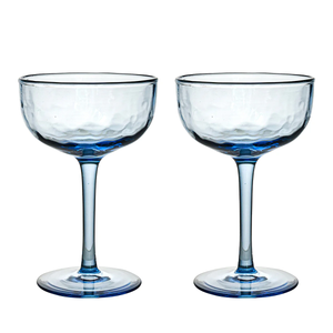 Two Puro Cocktail Coupe S/2 glasses by Juliska, featuring clear blue-tinted, textured bowls and slender stems, stand side by side against a white background—perfect for serving cocktails and elegantly packaged in a gift box.