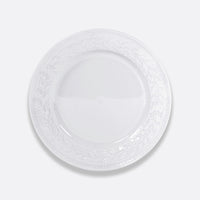 The Bernardaud Louvre Dinnerware features a white plate with a raised embossed laurel leaf pattern around the rim, inspired by Renaissance motifs and French architecture.