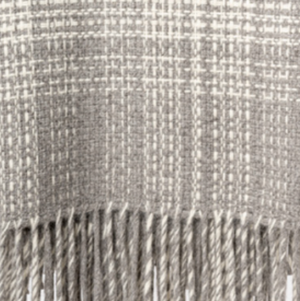 A close-up of the Rustic Alpaca Plaid Throw by Thread & Butter, featuring a beige and white plaid pattern, long twisted fringe, and expertly woven in Peru from luxurious alpaca fibre.