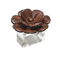 The Kim Seybert Begonia Napkin Rings Set of 4 features large dark brown flowers with petal and bead accents atop a clear rectangular base, adding a decorative touch to any table setting.