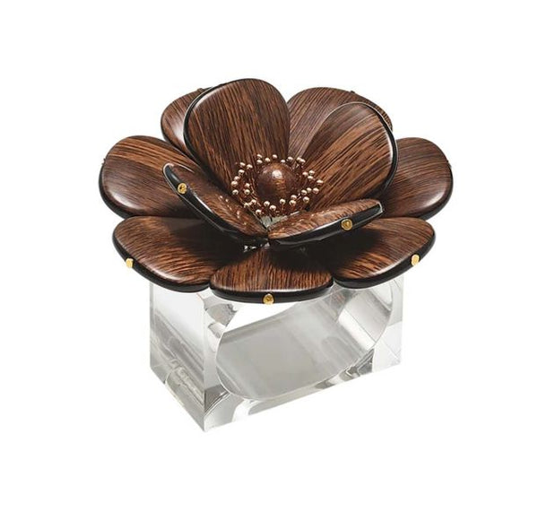 The Kim Seybert Begonia Napkin Rings Set of 4 features large dark brown flowers with petal and bead accents atop a clear rectangular base, adding a decorative touch to any table setting.