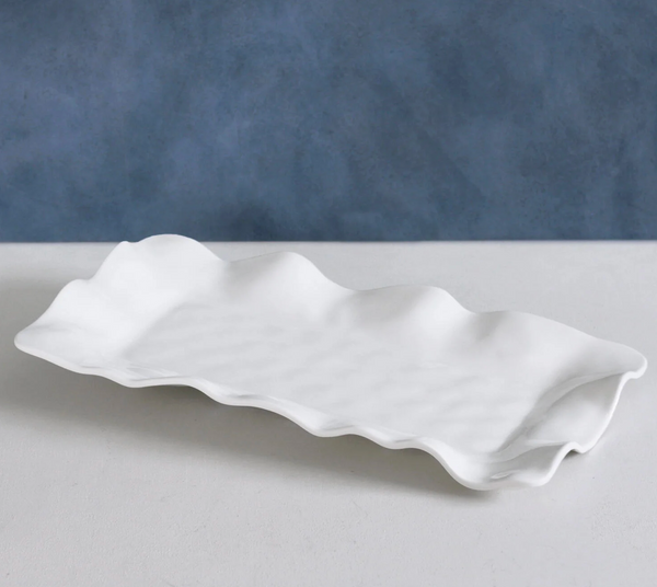 The Beatriz Ball Vida Havana Melamine Rectangular Tray with wavy edges is displayed on a white surface against a blue textured background.