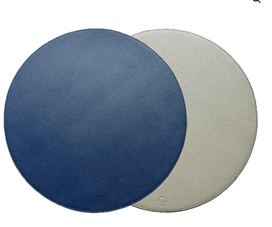 Two overlapping Reversible Placemats from Von Gern Home, one blue and one light gray, add elegance to a white table setting.