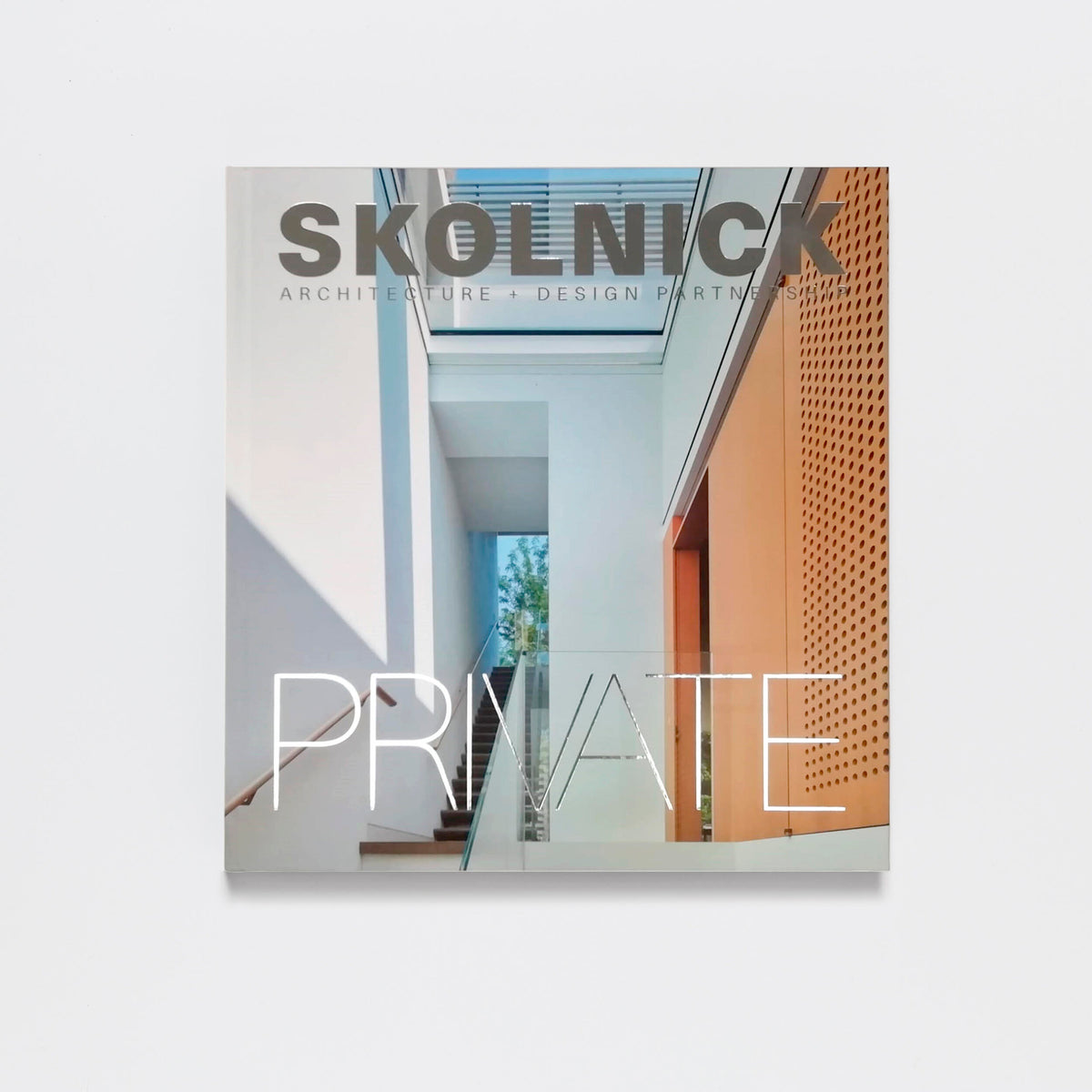Skolnick: Architecture & Design Partnership by Pointed Leaf Press appears over a striking modern staircase, illustrating the innovative style embodied by this New York architectural firm.