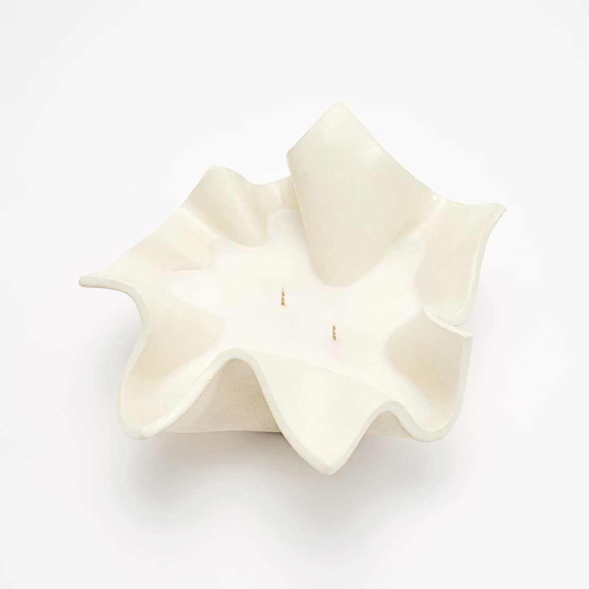 The Joy Candle Raw Blanc by Dumae is a white, sculptural candle with two wicks, crafted from soy-coconut wax and featuring an abstract wavy-edged bowl design.