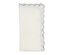 The Arches Napkin Set of 4 by Kim Seybert features folded white linen napkins with one scalloped, embroidered edge in wavy gray stitching, shown against a plain white background.