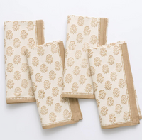 The Anika Napkin Set of 4 - Beige by Pomegranate features artisan-crafted beige napkins with a light brown tree block print and solid brown border, elegantly arranged on a white surface.