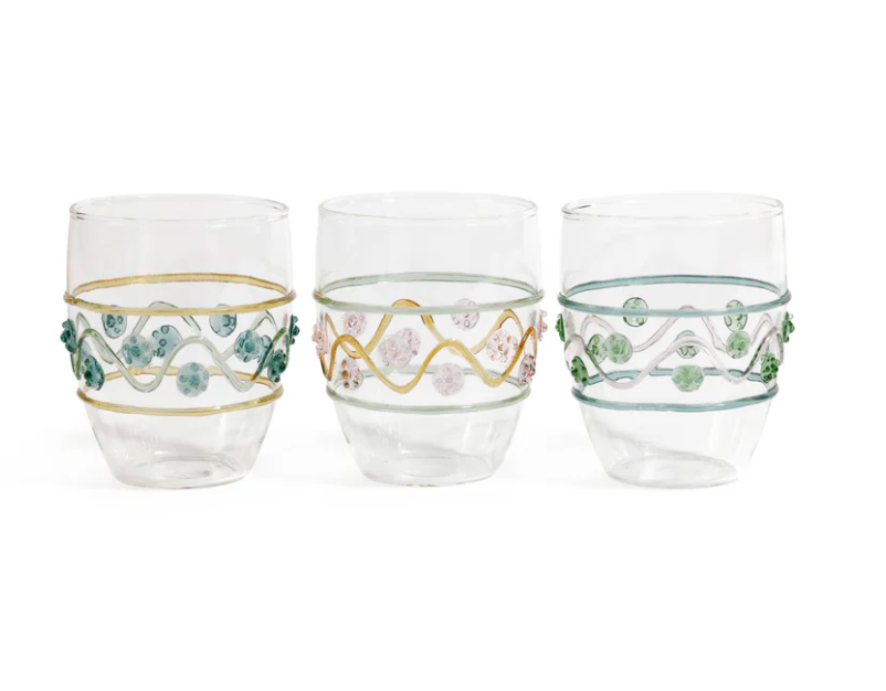 The Zodax Festa Tumbler Set includes three clear glass tumblers in green, amber, and pink tones, featuring decorative wavy lines and raised bead accents, displayed side by side against a white background.