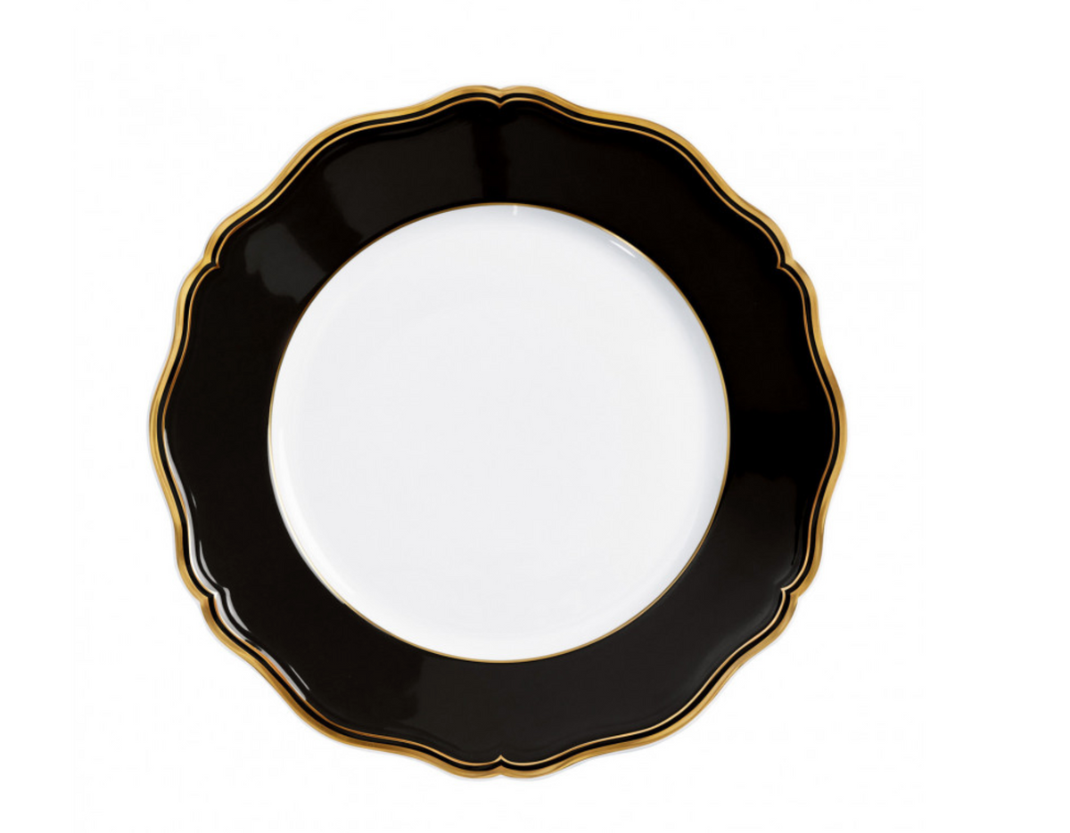 The Raynaud Mazurka Dinnerware Or Black plate features a round, white design with a wide, scalloped black rim and gold trim—photographed from above on white—perfect for luxury dining and showcasing French craftsmanship.