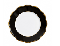 The Raynaud Mazurka Dinnerware Or Black plate features a round, white design with a wide, scalloped black rim and gold trim—photographed from above on white—perfect for luxury dining and showcasing French craftsmanship.