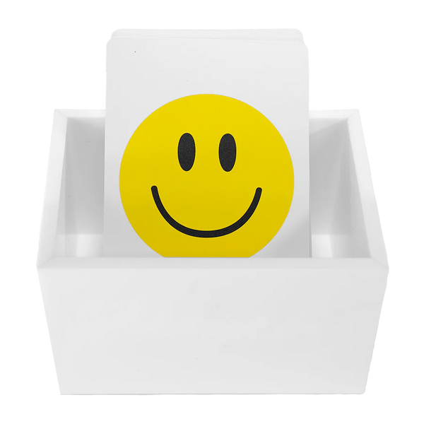 The Canasta Sets Canasta 2 Deck Holder is a white card holder displaying cards, with the front card showing a bold yellow smiley face—ideal for organizing or enhancing your Canasta card games.