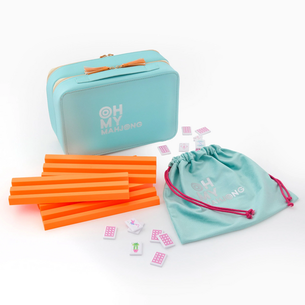 The Oh My Mahjong Mahjong Debutante Travel Tile Set features a turquoise zippered case, orange tile racks, a matching drawstring bag, and tiles—all displayed on white, perfect for portable play.