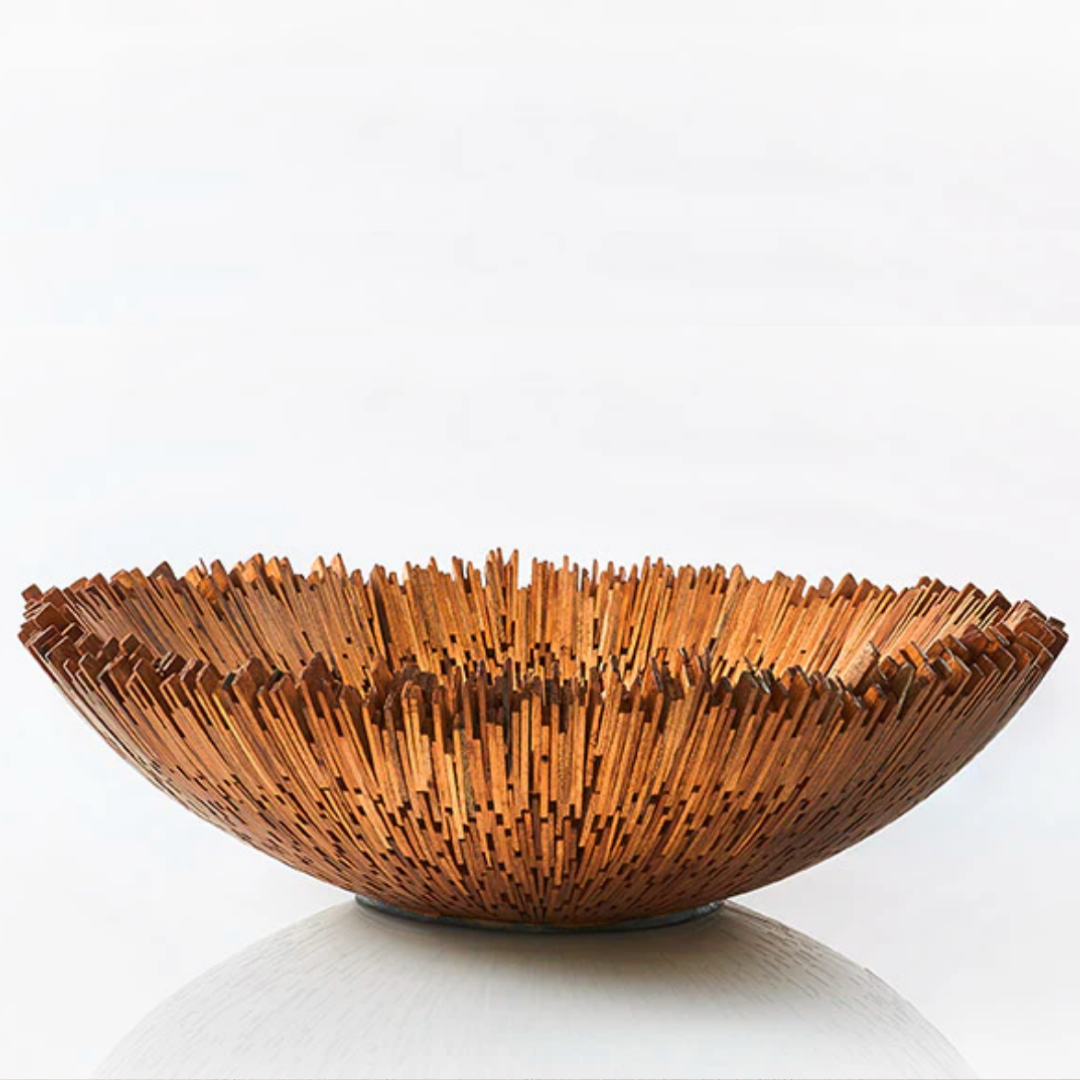 The Boracay Centerpiece Bowl by Lily Juliet features a handcrafted, spiky design of upright reclaimed mahogany sticks, creating a textured radial pattern. This decorative bowl is a striking centerpiece against a plain white background.