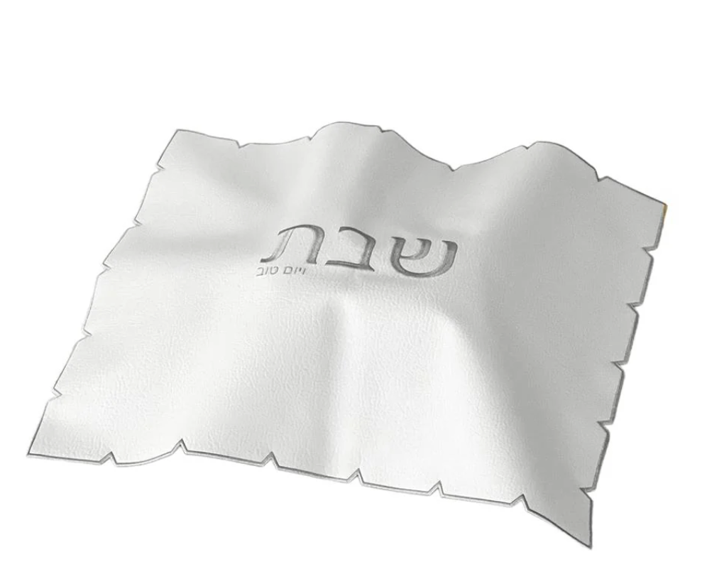 The BT-Shalom White Embroidered Leatherette Challah Cover—Silver features scalloped edges and central Hebrew text, making it an elegant Shabbat accent.