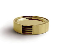 A round, gold-colored object with a ribbed exterior and a cutout section revealing layered inner components, placed on a white surface—this piece evokes the refined design of the Anna New York Striations Coasters s/4 in Holder - Gold, making it a perfect addition to any contemporary coaster collection.