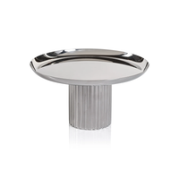 A Zodax Polished Nickel Cake Stand featuring a flat circular tray on a wide, vertically ribbed pedestal base.