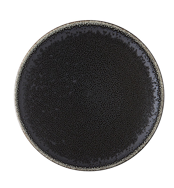 The Tourron Dinnerware Celeste plate by Jars - Rosenthal features a round, black glazed stoneware design with a textured surface and a gradient from dark center to lighter, speckled edges.