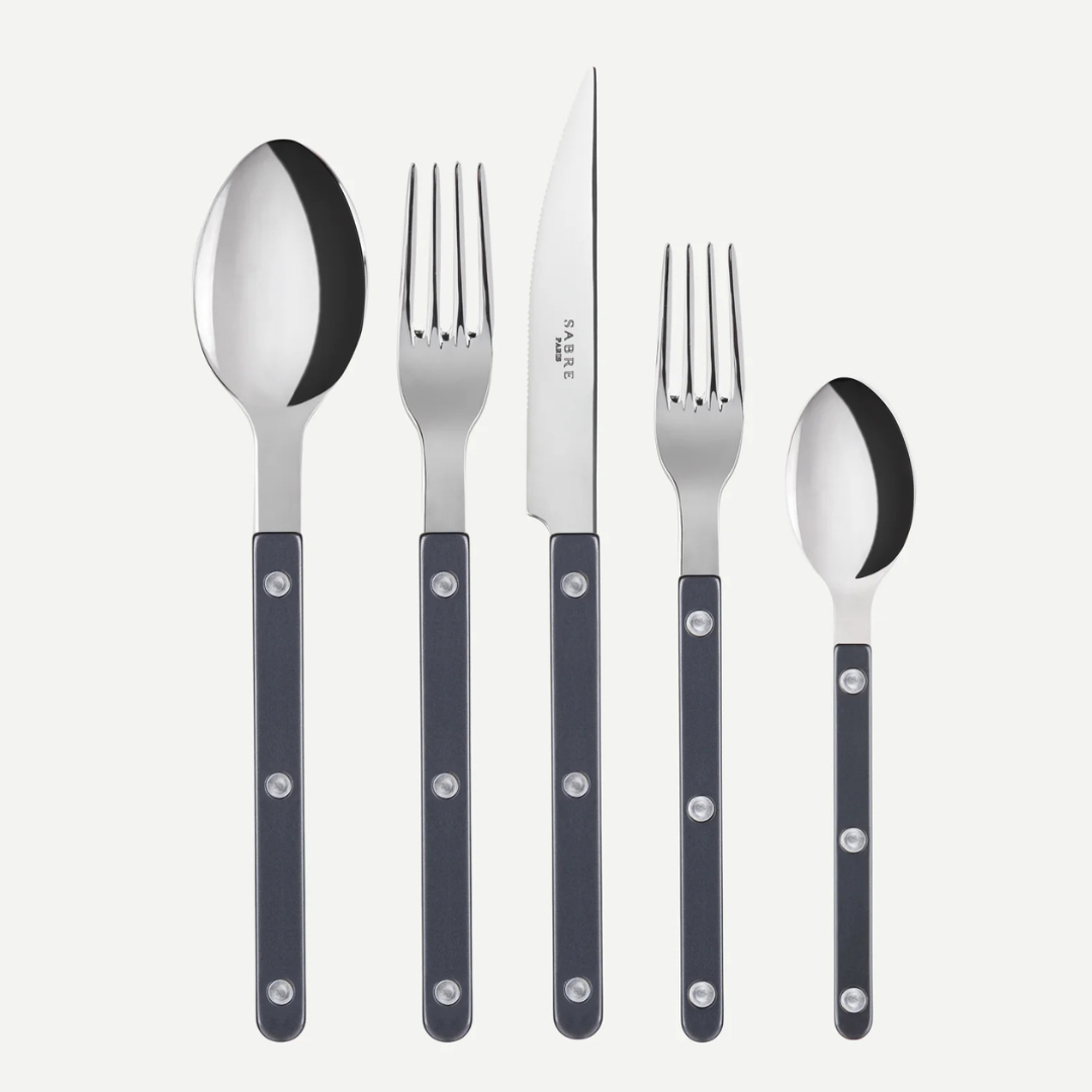 The Sabre Bistrot Pearly 5 Piece Setting - Shiny features black-handled cutlery with metal rivets: tablespoon, dinner fork, dinner knife, salad fork, and teaspoon shown upright on a white background. Made in France.