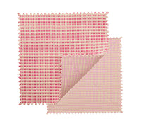 Two square fabric swatches in blush and pink with zigzag edges overlap, one partly folded to reveal both sides, highlighting the chic design of the Kim Seybert Duet Placemat Set of 4 - Blush & Pink.