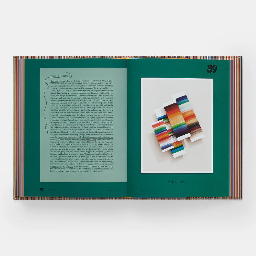 An open book titled "Paul Smith" by Phaidon/Hachette displays page 39 with text on the left and vivid horizontal stripes inspired by Paul Smith’s iconic designs on the right, set against a teal background.