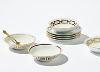Seven Ginori 1735 Catene Ebony Brown bowls, with gold geometric patterns, are stacked and arranged on a white background; one bowl comes with a gold spoon.