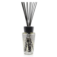 The Baobab Pearls Diffuser features a clear glass bottle with small raised dots, black reeds, a black cap, and a front label. Filled with fragrance liquid, it blends elegance and luxury for any space.