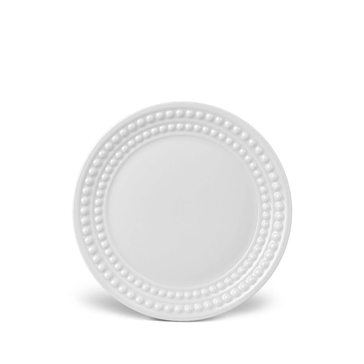 A white charger plate from the Perlée White Dinnerware collection by L'Objet, crafted in Limoges porcelain with a beaded border, is shown against a white background.