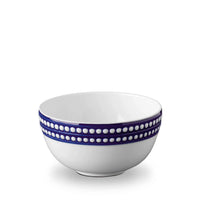 The L'Objet Perlèe Blue Dinnerware features a white ceramic bowl with two blue bands and raised white dots around the rim, reflecting classic blue and white style.