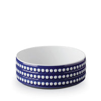 The Perlèe Blue Dinnerware bowl by L'Objet features a white interior, blue exterior, and three rows of raised white dots around the sides, echoing classic blue and white dinnerware. The bowl is shown against a plain white background.