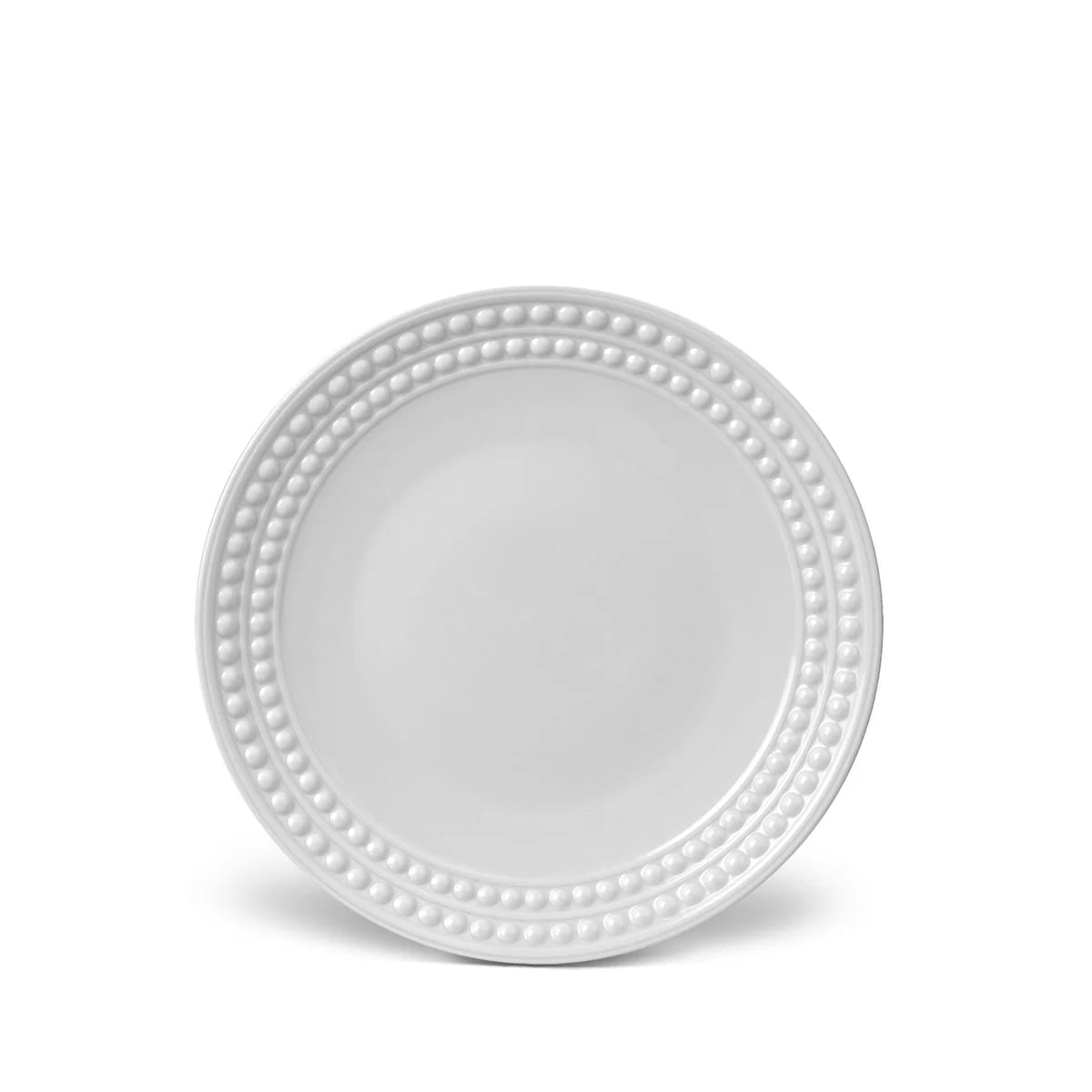 A round, white L'Objet Perlèe White Dinnerware charger plate features a decorative raised bead pattern along the rim, displayed on a plain white background.