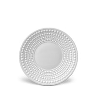 The Perlèe White Dinnerware charger plate by L'Objet features concentric raised dot patterns around the rim, crafted in white ceramic for an elegant, minimalist look.