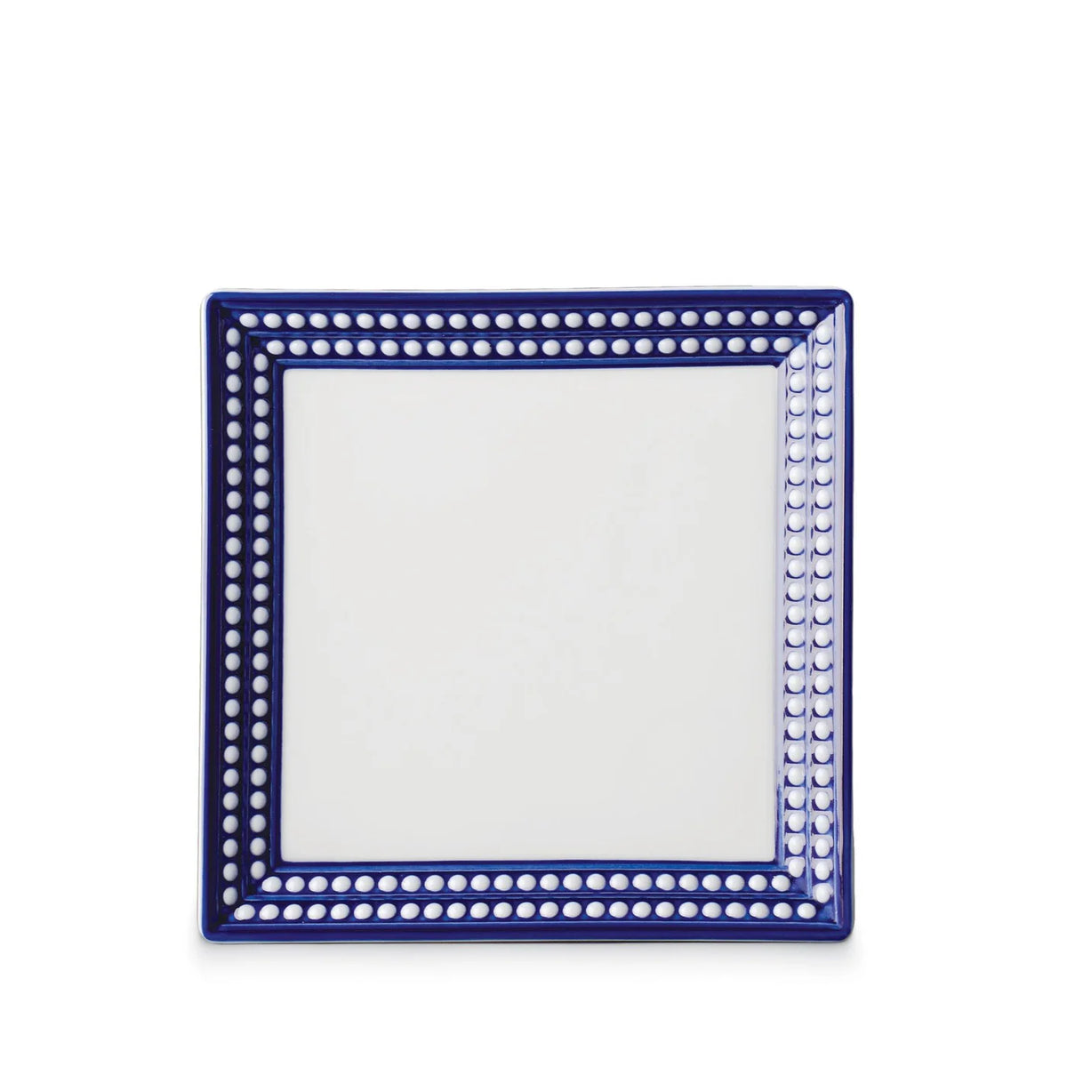 The Perlèe Blue Dinnerware by L’Objet is a square Limoges porcelain plate with a white center and a blue border accented by white dots—an elegant, modern choice for fans of blue and white dinnerware.