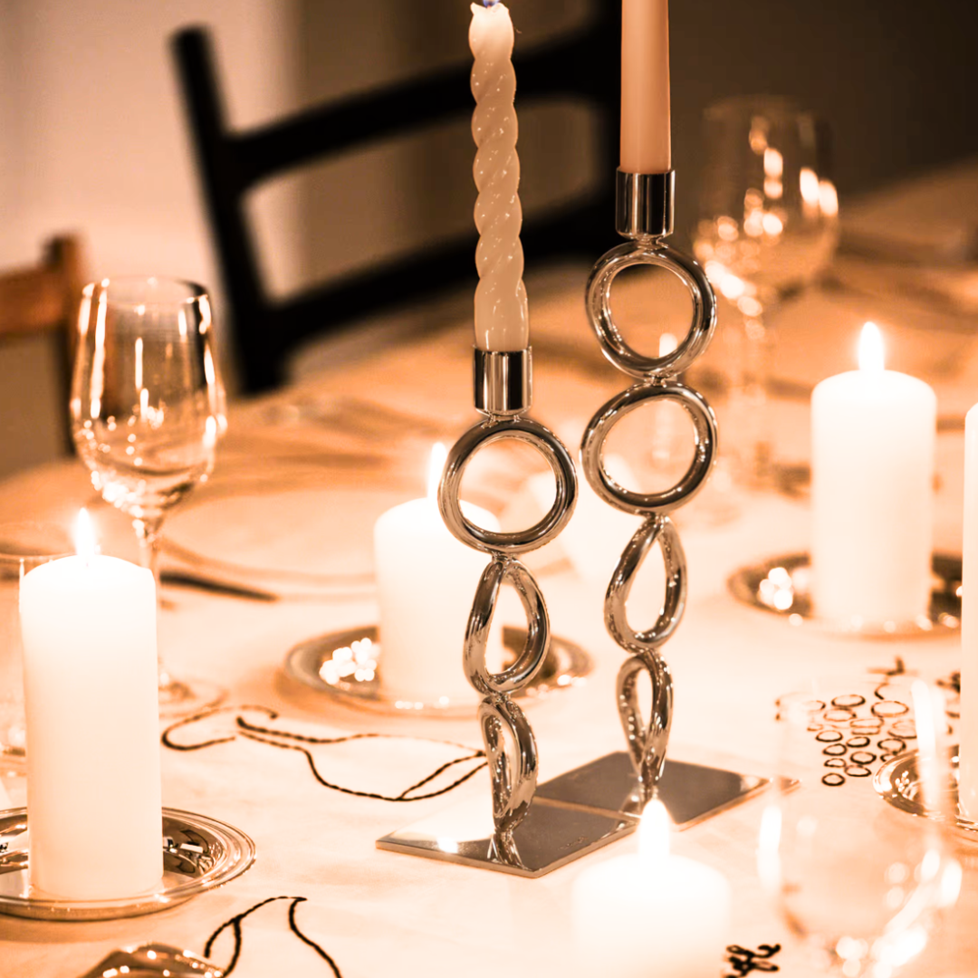 Candles on a table with wine glasses and elegant Christofle Vertigo Silver Plated Candlesticks.