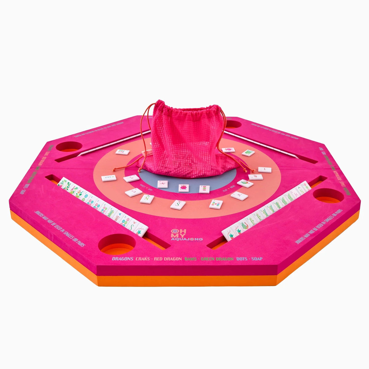 The Mahjong Aqua Pool Mat by Oh My Mahjong is an octagonal pink and orange set with tile racks, holders, a center tile area, red drawstring bag of tiles—ideal for gaming anywhere on this portable mat.