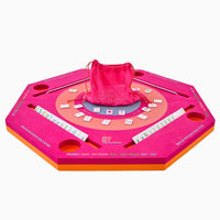 The Mahjong Aqua Pool Mat by Oh My Mahjong is an octagonal pink and orange set with tile racks, holders, a center tile area, red drawstring bag of tiles—ideal for gaming anywhere on this portable mat.