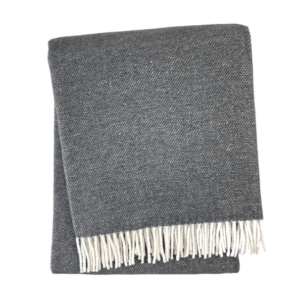 The A Soft Idea Pixel Throw in dark gray features a white fringe on one edge and is displayed folded on a white background. This stylish throw is machine washable for easy care.