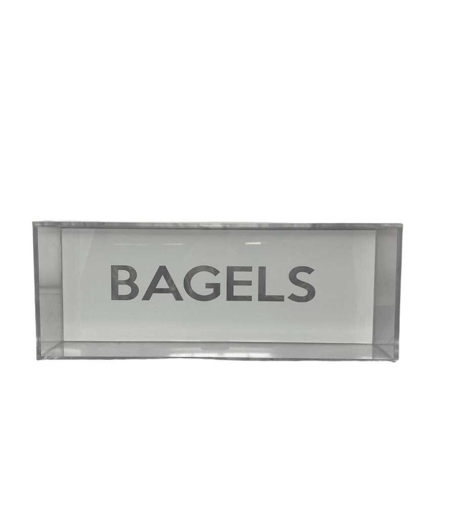 The Eye Candy Bagel Tray is a sleek, rectangular box made from silver marble, food-safe acrylic. "BAGELS" is boldly printed in uppercase on the front, making it ideal for display and organization. The tray appears empty to showcase contents.