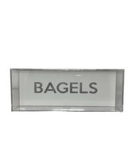 The Eye Candy Bagel Tray is a sleek, rectangular box made from silver marble, food-safe acrylic. "BAGELS" is boldly printed in uppercase on the front, making it ideal for display and organization. The tray appears empty to showcase contents.