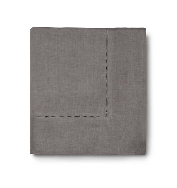 The Sferra Festival Tablecloth is a neatly folded gray fabric with a decorative hemstitch border, shown against a white background.