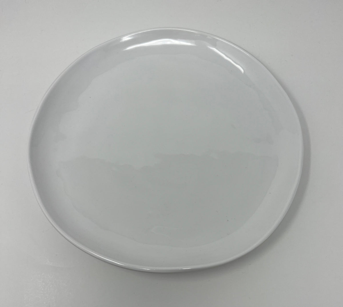 The Relish Simple White Melamine Dinnerware, a best seller, features a plain, round plate with a smooth, glossy finish. Set against a white background, it appears clean and is dishwasher safe for easy care.