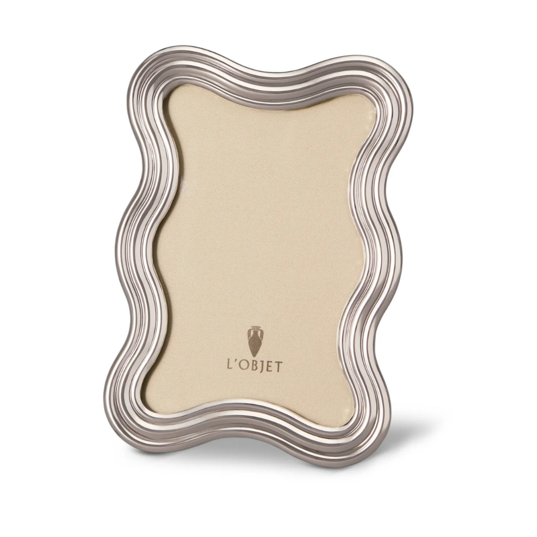 The L’Objet Ripple Frame Platinum features a wavy, contoured border with an empty beige center and the L’Objet logo in gold at the bottom. The frame stands upright against a white background.