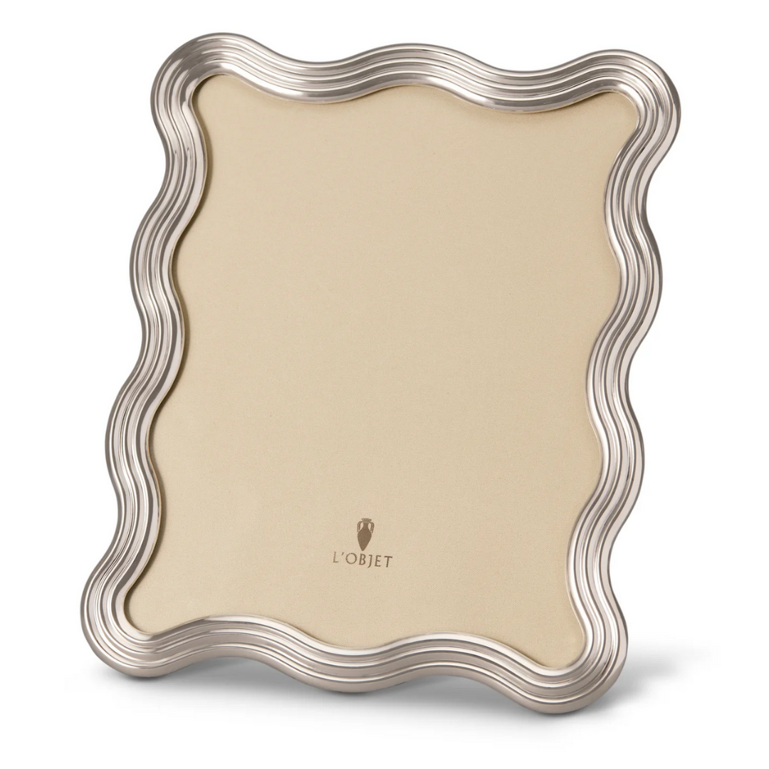 The L'Objet Ripple Frame Platinum features a wavy platinum-toned border, a beige center, and the L'Objet logo near the bottom. This modernist decorative frame stands upright against a plain white background.