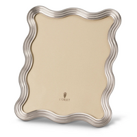 The L'Objet Ripple Frame Platinum features a wavy platinum-toned border, a beige center, and the L'Objet logo near the bottom. This modernist decorative frame stands upright against a plain white background.