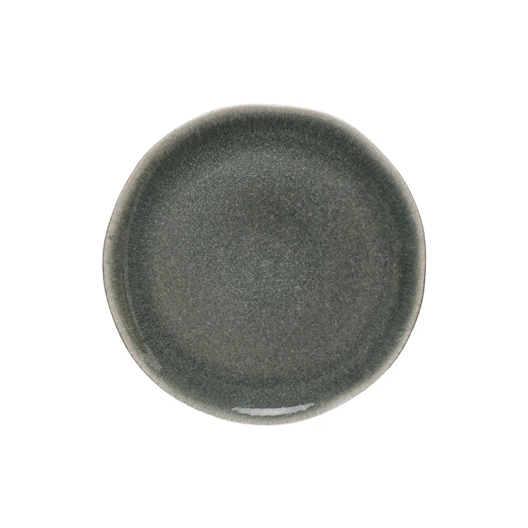 A round, dark gray Maguelone Orage stoneware plate by Jars - Rosenthal with a slightly irregular rim, viewed from above on a white background.