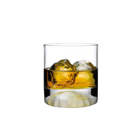 A Club Drinkware high ball glass by Nude Glassware, crafted from lead-free crystal, filled with golden whiskey and two large ice cubes, sits against a plain white background.