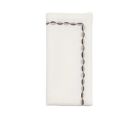 The Swag Napkin Gunmetal & Silver Set of 4 by Kim Seybert features folded white linen napkins accented with embroidered gunmetal and silver ovals along two adjacent edges, creating a stylish L-shape—perfect for elegant holiday gatherings.